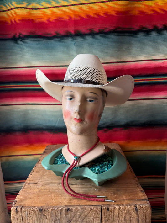 Mannequin head with a cowboy hat against a colorful striped fabric background